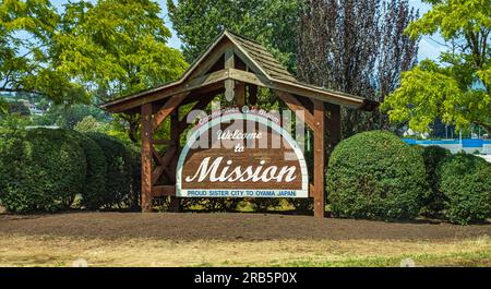 Holztafel mit Begrüßungsschild. Ein Schild heißt die Fahrer in der kleinen Gemeinde Mission British Columbia Canada willkommen. Reisefoto, Niemand-J Stockfoto