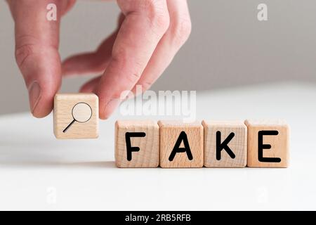 Das Wort FAKE, Dinkel mit hölzernen Buchstabensteine, über einem weißen Hintergrund. Stockfoto