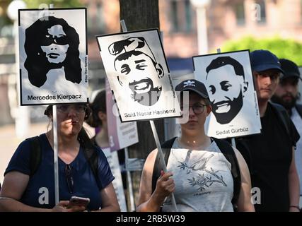 07. Juli 2023, Hesse, Wiesbaden: Bilder der Opfer des Hanau-Angriffs werden während einer Kundgebung auf dem Gelände von Dern aufgehalten. Unter dem Motto „Keine Gerechtigkeit ohne Konsequenzen!“ In der Initiative vom 19. Februar hatte Hanau eine Demonstration gefordert. Ein 43-jähriger Deutscher hatte am 19. Februar 2020 neun Menschen in Hanau erschossen, aus rassistischen Motiven. Dann tötete er seine Mutter und sich selbst. Seit dem Sommer 2021 beschäftigen sich die Mitglieder des staatsparlaments im Untersuchungsausschuss mit dem Angriff. Foto: Arne Dedert/dpa - ACHTUNG: Nur zur redaktionellen Verwendung und nur mit vollständiger Erwähnung der oben genannten Punkte Stockfoto