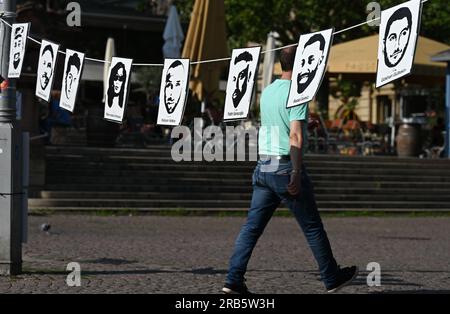 07. Juli 2023, Hesse, Wiesbaden: Bilder der Opfer des Hanau-Angriffs hängen an der Leine einer Kundgebung auf dem Gelände von Dern. Unter dem Motto „Keine Gerechtigkeit ohne Konsequenzen!“ In der Initiative vom 19. Februar hatte Hanau eine Demonstration gefordert. Ein 43-jähriger Deutscher hatte am 19. Februar 2020 neun Menschen in Hanau erschossen, aus rassistischen Motiven. Dann tötete er seine Mutter und sich selbst. Seit dem Sommer 2021 beschäftigen sich die Mitglieder des staatsparlaments im Untersuchungsausschuss mit dem Angriff. Foto: Arne Dedert/dpa - ACHTUNG: Nur zur redaktionellen Verwendung und nur mit vollständiger Erwähnung der Stockfoto