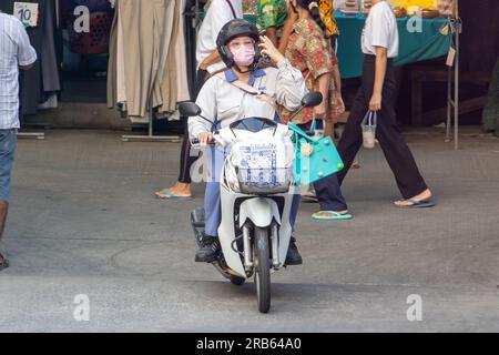 SAMUT PRAKAN, THAILAND, MÄRZ 03 2023, Eine Frau mit Gesichtsmaske fährt ein Motorrad Stockfoto