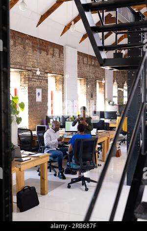 Glückliche afroamerikanische Kollegen, die über Arbeit und Mittagessen im Kreativbüro sprechen. Business, Brainstorming, Essen und Teamarbeit, unverändert. Stockfoto