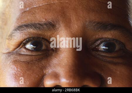 Augenporträt einer afroamerikanischen Seniorin. Senioren-Lebensstil, Entspannung, Ruhestand und Wohlbefinden in der Natur, unverändert. Stockfoto