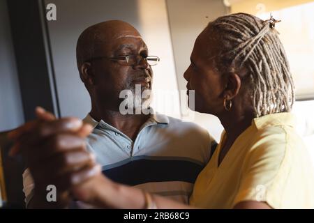 Glückliches Senior-afroamerikanisches Paar, das zu Hause umarmt und tanzt. Seniorenleben, Entspannung und Ruhestand, unverändert. Stockfoto