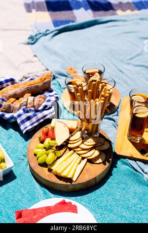 Nahaufnahme von blauen Decken mit Lebensmitteln auf Schneidebrettern und Tellern. Picknick, Zeit zur freien Verfügung, Getränke und Speisen, unveränderte Speisen. Stockfoto