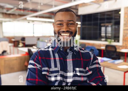 Portrait eines glücklichen afroamerikanischen Geschäftsmanns, der die Waffen kreuzt und im Büro lächelt. Ungezwungene Geschäfte, Selbstvertrauen und Arbeit, unverändert. Stockfoto