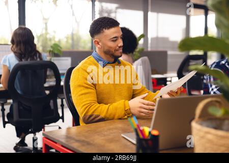 Verschiedene Geschäftsleute, die an Schreibtischen sitzen und Computer im Büro verwenden. Ungezwungene Geschäfte, Kommunikation und Arbeit, unverändert. Stockfoto