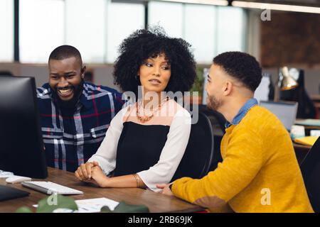 Verschiedene Geschäftsleute, die im Büro über die Arbeit und die Nutzung von Computern diskutieren. Business, Teamwork, Kommunikation und Arbeit. Stockfoto