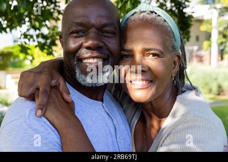 Portrait eines glücklichen älteren afroamerikanischen Paares, das im sonnigen Garten lächelt und sich umarmt. Seniorenleben, Glück, Ruhestand und häusliches Leben, Uni Stockfoto
