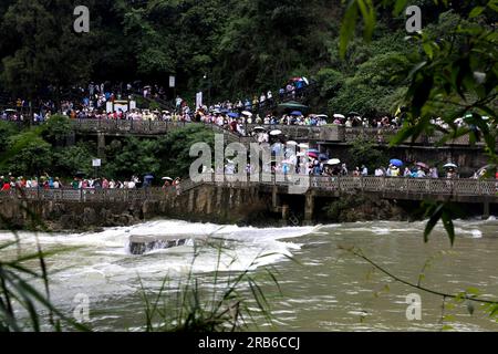 ANSHUN, CHINA - 7. JULI 2023 - Touristen kühlen sich ab, indem sie im Wasser vor dem Huangguoshu Wasserfall in Anshun, Provinz Guizhou, China, 7. Juli, Stockfoto