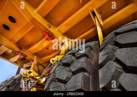 Überarbeitung der Aufhängung, Doppelachse unter einem riesigen, brandneuen gelben Bergbaufahrzeug, oben auf einem Anhänger, der in einer Diamantenmine geliefert wurde Stockfoto