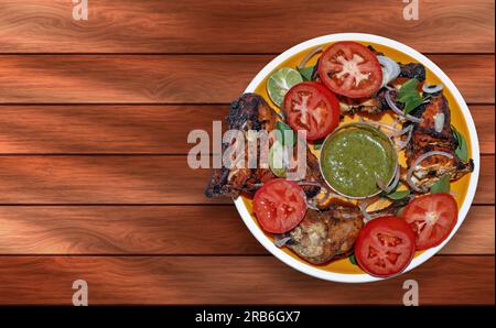 Gegrilltes Hähnchen mit Gemüse und Sauce auf einem Holztisch. Stockfoto