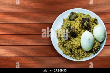 Hammelbiryani mit Ei auf weißem Teller auf Holztisch. Ein beliebtes indisches nicht-vegetarisches Gericht. Draufsicht Stockfoto