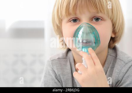 Kranker kleiner Junge mit Vernebler zur Inhalation in Innenräumen Stockfoto