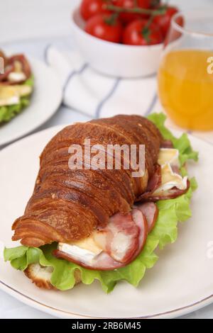 Leckeres Croissant mit Brie-Käse, Schinken und Speck auf dem Tisch Stockfoto