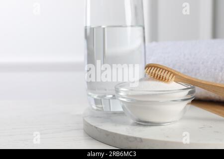 Bambuszahnbürste, Schüssel mit Backpulver und Glas Wasser auf weißem Tisch, Platz für Text Stockfoto