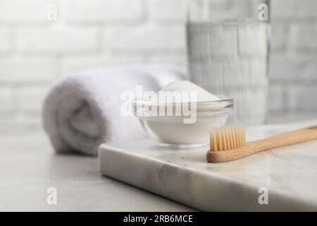 Bambuszahnbürste und Glasschüssel mit Backpulver auf einem hellen Tisch, Platz für Text Stockfoto