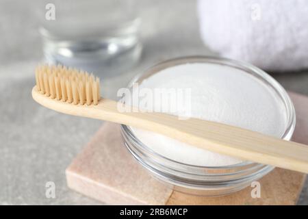 Bambuszahnbürste und Glasschüssel mit Backpulver auf einem leichten Tisch, Nahaufnahme Stockfoto