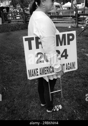 Ein Unterstützer des ehemaligen US-Präsidenten Donald Trump vertreibt Schilder für die Neuwahl von Trump zum Präsidenten im Jahr 2024. Stockfoto