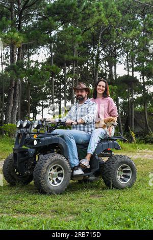 Porträt eines jungen Ehepaars, das auf einem Quad im Wald sitzt Stockfoto