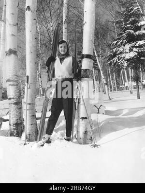 Lake of Bay, Ontario, Kanada: ca. 1956 Eine junge Frau mit ihren Langlaufskiern steht in einem Birkenhain. Stockfoto