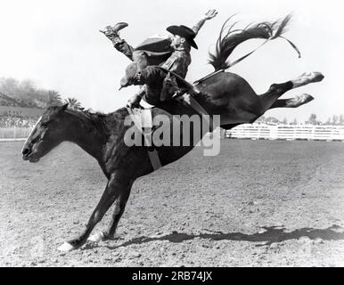 Kansas City, Missouri: ca. 1950. Der Bareback-Fahrer muss sich für eine gewalttätige Achtsekundenfahrt am Lederhandgriff festhalten. Er muss das ungezügelte Pferd beim ersten Sprung aus dem Fallschirm über die Schultern treiben und es während der Fahrt gut lecken, um einen hohen Punktestand zu erzielen. Er kann mit seiner freien Hand kein Stück des Pferdes berühren. Das Pferd hat keine Regeln, was es tun kann, um ihn zu verlassen. Stockfoto