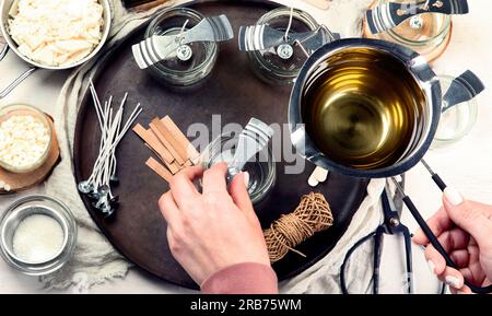 Set für hausgemachte Kerzen aus natürlichem Sojawachs, Frau, die dekorative Kerzen mit Aroma am Tisch macht Stockfoto