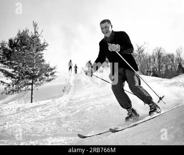 East Corinth, Vermont: ca. 1952. Ein Skifahrer in Vermont, der bergab fährt und ein großes Grinsen im Gesicht hat. Stockfoto