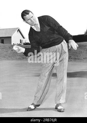 New Jersey: ca. 1953 Ein Mann, der mit einer anderen Sportausrüstung posiert und Ähnlichkeiten mit der Körperhaltung zeigt. Hier benutzt er einen Baseball. Stockfoto