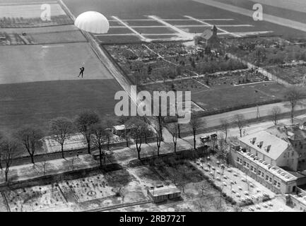 Deutschland: 24. Mai 1931 Willi Ruge ist bestrebt, die ersten Selbstporträts vom Fallschirm zu machen, wenn er aus einem Flugzeug springt. Hier fotografiert er sich selbst, während er hinabsteigt, ist aber auch besorgt über die Hochspannungsleitungen unten. Stockfoto