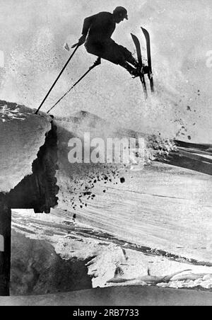 Chamonix, Schweiz: 25. Dezember 1937. Ein Skifahrer führt bei diesem Weihnachtsfoto einen gewagten Stunt abseits des Berges durch. Stockfoto