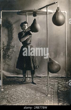 Vereinigte Staaten: ca. 1890 Eine junge Frau im Rock trainiert mit Boxhandschuhen und einem Boxsack. Stockfoto