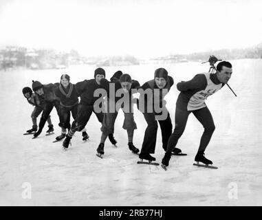 Lake Placid, New York: 27. Dezember 1927. Joe Moore, Hallen-Eiskunstlauf-Champion, leitet eine Gruppe von Followern auf dem Eis und trainiert für die internationalen Meisterschaftsrennen in Newburgh, New York. Stockfoto