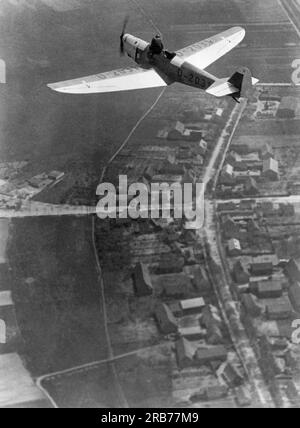 Deutschland: 24. Mai 1931 Willi Ruge ist bestrebt, die ersten Selbstporträts vom Fallschirm zu machen, wenn er aus einem Flugzeug springt. Hier macht er ein Foto von seinem Flugzeug, während sein Kollege Herr Boettcher seinen Sitz im anderen Flugzeug verlässt und sich in Vorbereitung auf den Sprung in die Nähe des Piloten bewegt. Stockfoto