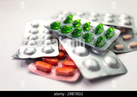 Große Anzahl von Pillen und Tablettenblättern auf weißem Hintergrund angeordnet. Die Tabletten sind in verschiedenen Farben und Größen, und die Tablettenbögen sind mit w gekennzeichnet Stockfoto