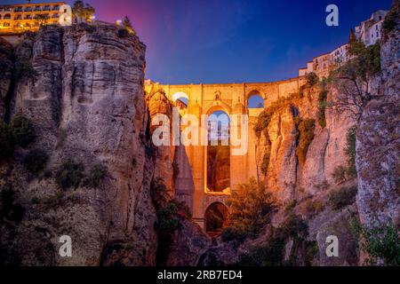 Spektakulärer Blick auf die Neue Brücke in Ronda, Malaga, Spanien, beleuchtet in der Dämmerung vom unteren Teil der Stadt Stockfoto