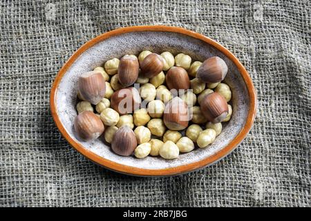 Reife Filbertkerne und Haselnüsse in einer Schüssel auf Leinenhintergrund. Gesunde Ernährung, Ernährung. Speicherplatz kopieren. Geringe Schärfentiefe. Draufsicht. Selecti Stockfoto