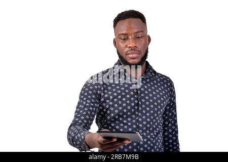 Ein junger bärtiger Mann, der auf weißem Hintergrund mit einem Tablet steht. Stockfoto