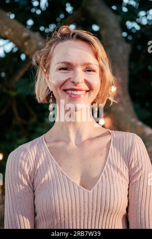 Vertikales Einzelbild einer Frau mittleren Alters, die mit freundlichem Ausdruck in die Kamera schaut. Glückliche weiße, reife Frau mit stolzer und positiver Einstellung. Mittelgroße Erwachsene Frau, die lächelnd posiert. Hochwertiges Foto Stockfoto