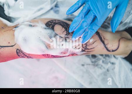 Frisches Tattoo mit hohem Winkel, das mit weißem Schaum gereinigt wird. Reinigungsvorgang eines neuen Tätowierens. Professionelles Tattoo-Studio. Hochwertiges Foto Stockfoto