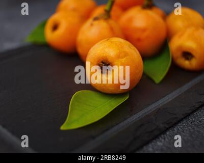 Obstloquat Medlar isoliert auf dunklem Tischhintergrund. Auch Nispero und Eriobotrya japonica genannt. Schließen. Stockfoto