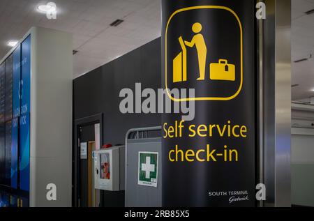 Ein Schild mit der Aufschrift „Self Service Check-in“ am Flughafen London Gatwick, South Terminal, West Sussex, Großbritannien. Stockfoto