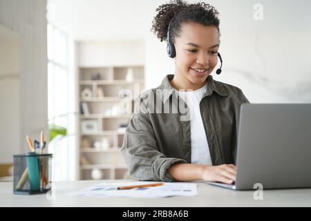 Lächelnde, birassische Schüler lernen zu Hause online und tragen ein Headset für Fernstudium. Fernunterricht. Stockfoto