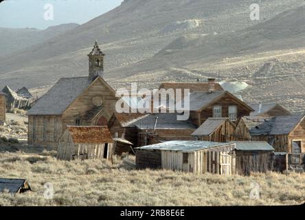 Bodie ist heute ein California State Park und ist vielleicht das beste Beispiel einer Geisterstadt aus der Zeit des Goldrauschs im Wilden Westen Amerikas. Etwa fünf Prozent der ursprünglichen Holz- und Ziegelgebäude befinden sich noch immer in einem Zustand von festgestelltem Zerfall (weiterer Zerfall wird verhindert, aber es werden keine weiteren Reparaturen durchgeführt). Die Straße zu dieser gut erhaltenen historischen Stätte liegt abseits der I-395 zwischen Lee Vining im Süden und Bridgeport im Norden entlang der Grenze zwischen Kalifornien und Nevada in einer kargen Reihe niedriger Hügel. Die Höhe beträgt 8.300 Fuß und der Ort ist fast das ganze Jahr über windgepeitscht. Alle bis auf die letzten drei Meilen sind gepflastert. Stockfoto