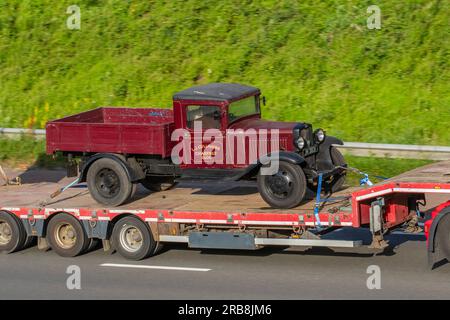 1933 30s Thirties Maroon Bedford Sedan Drop-Side Van, JN 3831 BEDFORD 2 TONNEN TRUCK, L.J. Cullimore, Wotton-under-Edge, Glos, wird in einem Nooteboom-Trailer transportiert und fährt auf der Autobahn M6 im Großraum Manchester, Großbritannien Stockfoto