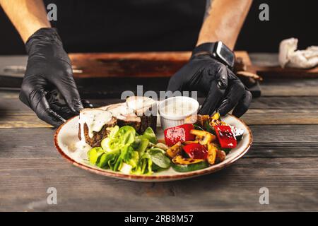 Koch Veredelung seinen Teller und am Tisch fast servierfertig Stockfoto