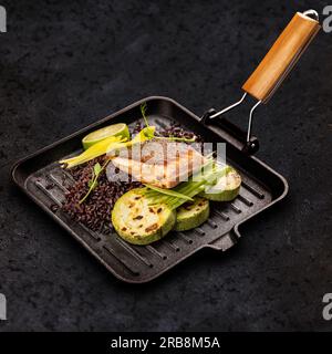 Gebratenes Fischfilet serviert mit wildem Reis und gegrillter Zucchini Stockfoto