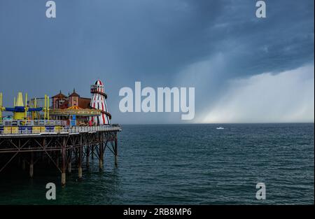 Brighton UK 8. Juli 2023 - bedrohliche dunkle Wolken über dem Brighton Palace Pier, während Donner über Teile des Vereinigten Königreichs wehen : Credit Simon Dack / Alamy Live News Stockfoto