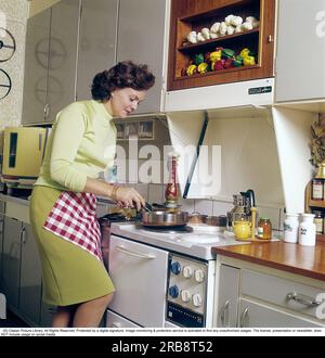 Haide Göransson (1928-2008) schwedisches Schauspieler- und Modemodell. Hier zu Hause, in der Küche, wo sie am Herd steht und kocht, in der Ecke befindet sich eine runde Spülmaschine der Marke electrolux, auch runde Dose genannt, was leicht zu verstehen ist, da die Spülmaschine eine seltsame runde Form hat. Schweden 1968. Kristoffersson Stockfoto