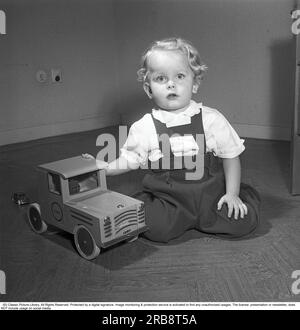 Kinder im 1950er. Jahrhundert. Ein kleiner Junge sitzt ordentlich gekleidet und gut gepflegt mit seinem Spielzeug, einem Brio Truck. Das Unternehmen Brio begann bereits Anfang des 20. Jahrhunderts mit der Herstellung von Holzspielzeug. Schweden 1951. Kristoffersson Ref. BB41-7 Stockfoto